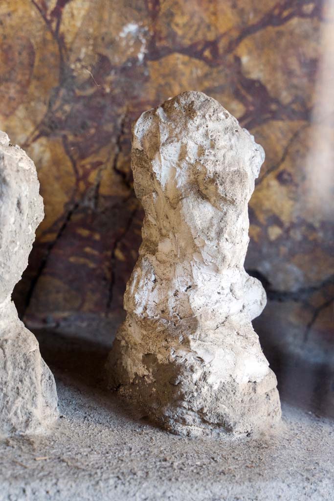 I.10.4 Pompeii. April 2022. 
Alcove 25, detail of plaster cast, seen on the left of centre, on the lararium or domestic shrine. (Image 1).
Photo courtesy of Johannes Eber.