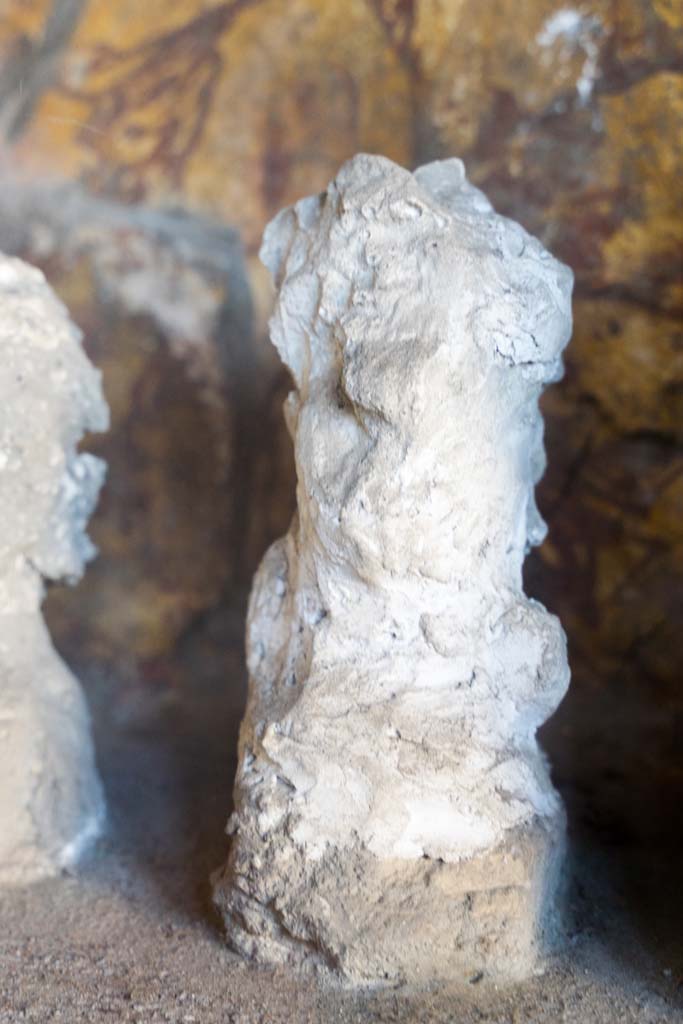 I.10.4 Pompeii. April 2022. 
Alcove 25, detail of plaster cast, seen on the left of centre, on the lararium or domestic shrine. (Image 2).
Photo courtesy of Johannes Eber.