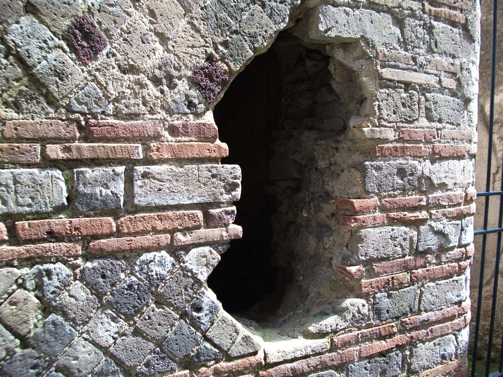 I.10.4 Pompeii. May 2010. P1, east wall, with ancient hole made by fugitives trying to escape in 79AD.
According to Allison, the 10 skeletons discovered in this corridor might have been part of the same party as the 3 skeletons found with a pick and a hoe in room 19 on the other side of the hole. 
They appear to have been people who probably suffocated whilst trying to escape during the final eruption. 
They included at least 3 children under the age of 5. 
The age of the children and the victims being on both sides of the wall and with tools would suggest they were probably victims rather than post-eruption intruders.
See Allison, P.M., 2004. Pompeian Households: An analysis of the material culture. Los Angeles: UCLA Cotsen Institute. (p. 24; p. 180).