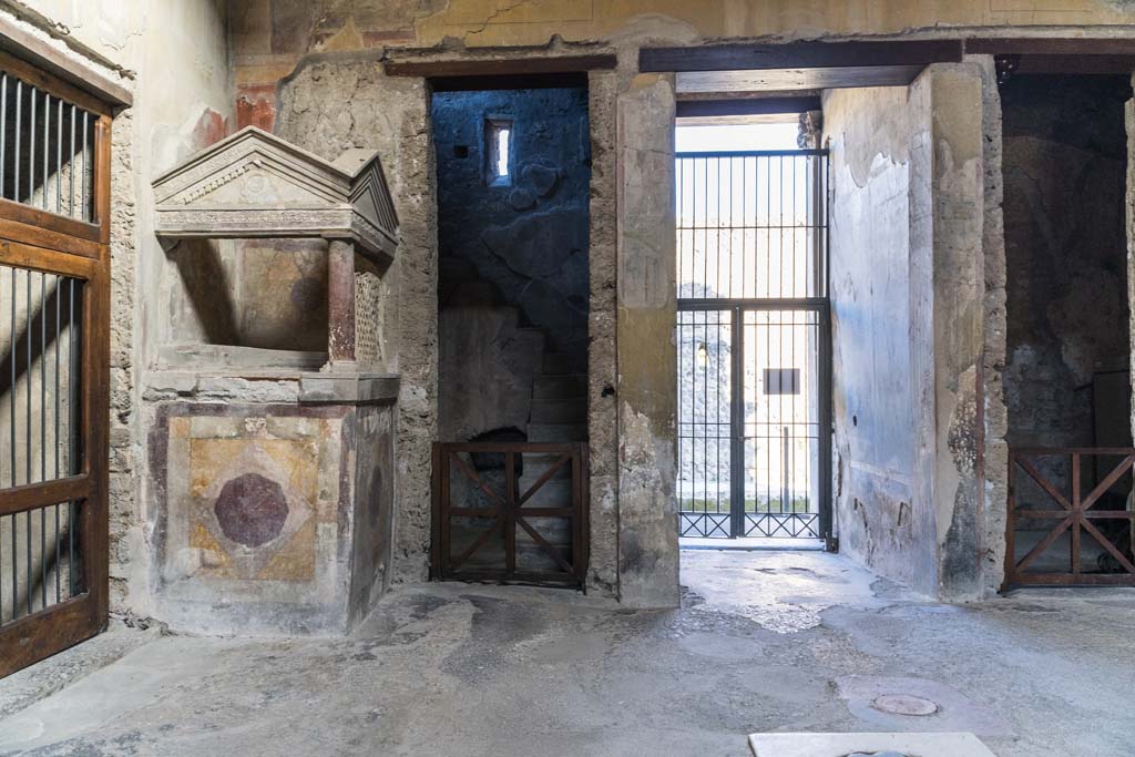 I.10.4 Pompeii. April 2022. Aedicula lararium with stucco decoration, in north-west corner of atrium. 
Behind is room 2 with stone stairs to an upper floor. Photo courtesy of Johannes Eber.