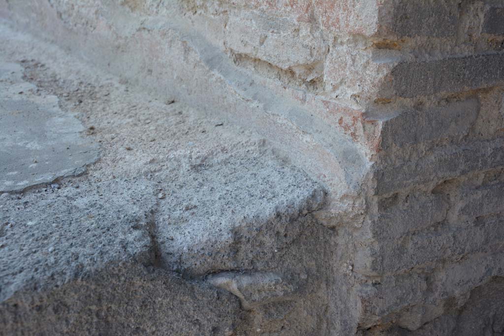 I.10.18 Pompeii. April 2017. Detail of remaining painted plaster at north end of bench seating on south side of entrance doorway. 
Photo courtesy Adrian Hielscher.