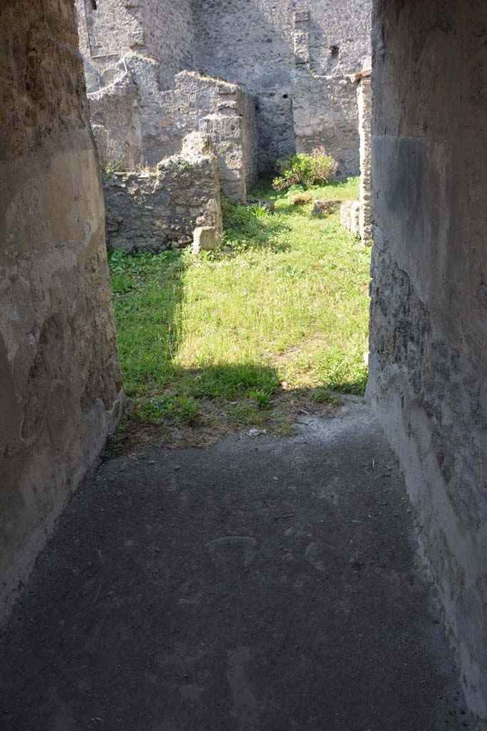 I.10.18 Pompeii. April 2017. Looking west from entrance corridor/fauces.
Photo courtesy Adrian Hielscher.
“The entrance doorway enters through the spacious entrance corridor with rustic flooring and walls covered with fine black plaster, into a small tuscanic atrium. Opening, on either side of the entrance corridor, were rooms 2 and 3, both with door-jambs painted in red, both lit by a rectangular window which opened in the east wall overlooking the roadway. 
The room to the left of the fauces/corridor (room 2), probably a cubiculum, was decorated with a low light red zoccolo topped with a narrow red band edged by white lines and decorated with white geometric patterns. The upper area of the wall was simple white rough plaster. 
The room to the right (room 3) was an oecus, it was decorated with a high pink zoccolo, above which the part of the wall had been left of rustic white plaster, equally rustic was the flooring.”
See Notizie degli Scavi, 1934, (p.341-4)