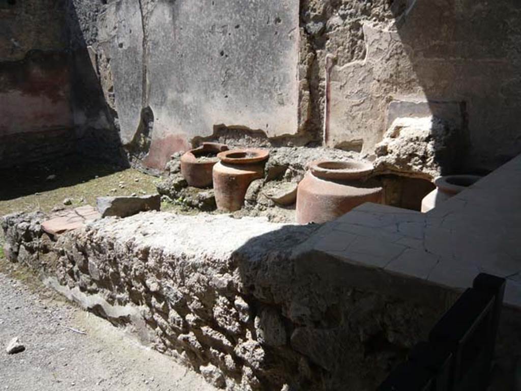 1.11.1 Pompeii. May 2015. West side with bar, remains of four urns and shelves for displaying drinking vessels.
Photo courtesy of Buzz Ferebee.