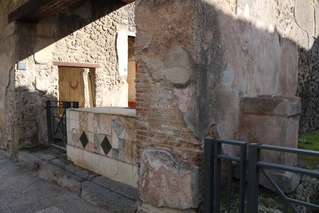 I.11.1 Pompeii. December 2018. 
Looking south-east towards entrance doorway, on left, and street altar in small roadway, on right. Photo courtesy of Aude Durand.