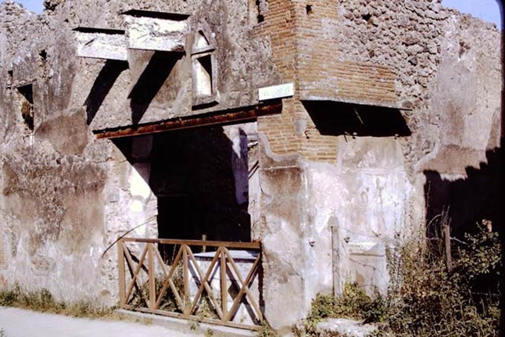 I.11.1 Pompeii. 1968. Entrance on Via dell’Abbondanza. Photo by Stanley A. Jashemski.  On the right, in the side vicolo, a street altar can be seen.
Source: The Wilhelmina and Stanley A. Jashemski archive in the University of Maryland Library, Special Collections (See collection page) and made available under the Creative Commons Attribution-Non Commercial License v.4. See Licence and use details.  J68f0371
According to Della Corte,  “Reg. II, ins.1, on high between doorways 1 and 2, a window was found (0.80m wide x 1.20m high), protected by a grating which remains in its place in reasonable state of preservation; beyond the described window and continuing towards the east, and it seems placed above doorways 2 and 3, a large roof was found a little knocked down from its original position, about 6m. long (but the eastern extremity was not yet discovered), and protruding by just over 2m.  At the rear of the wall of the façade of doorway 1, definitely in their place were the remains of the basins/tubs mentioned last month, putting all the fragments of one of them back into its place with its bottom. "
See Notizie degli Scavi, 1913, p.220.
(Reg. II, ins. 1. Tra I vani 1 e 2 in alto, si e scoperta una finestra (larga 0.80m. alta 1.20m) protetta da inferriata che resta tuttora al suo posto in discreto stato di conservazione; oltre la descritta finestra, procedende sempre verso oriente, e quindi imposta sul vani 2 e 3 come pare, si era rinvenuta, di poco abbattuta dalla sua originaria posizione, una grande tettoia, lunga per ora (non se ne era ancora scoperta l’extremita orientale) 6m, e sporgente per poco piu di m.2.  A tergo del muro di facciata del vano 1 si sono definitivamente assicurati al posto loro gli avanzi delle vasche accennate il mese scorso, rimettendo a posto interamente i frammenti di una di esse col relativo fondo.”)