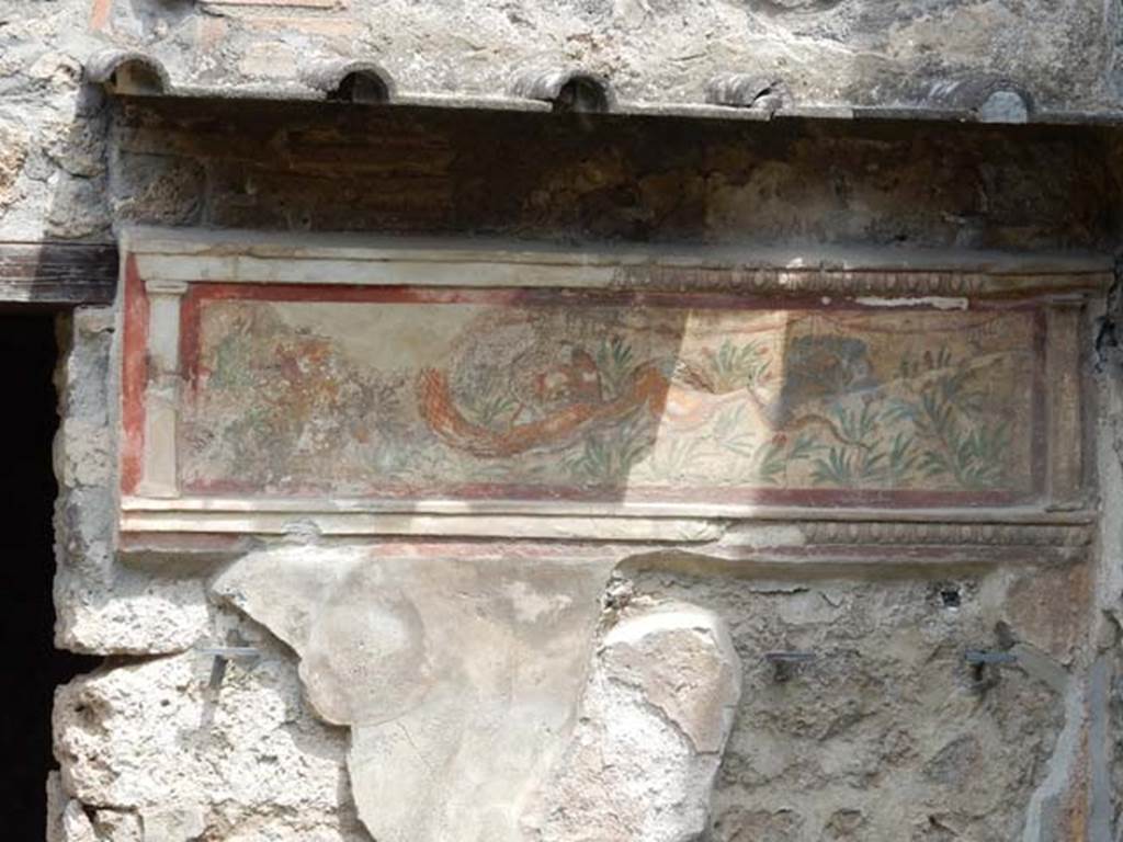 I.11.11 Pompeii. May 2017. Lararium on north wall of thermopolium. Photo courtesy of Buzz Ferebee.
A stucco border surrounding a serpent moving left to a round altar. In the background are green plants with red flowers.  See Fröhlich, T., 1991. Lararien und Fassadenbilder in den Vesuvstädten. Mainz: von Zabern. (L21, T:14,1:24,2).