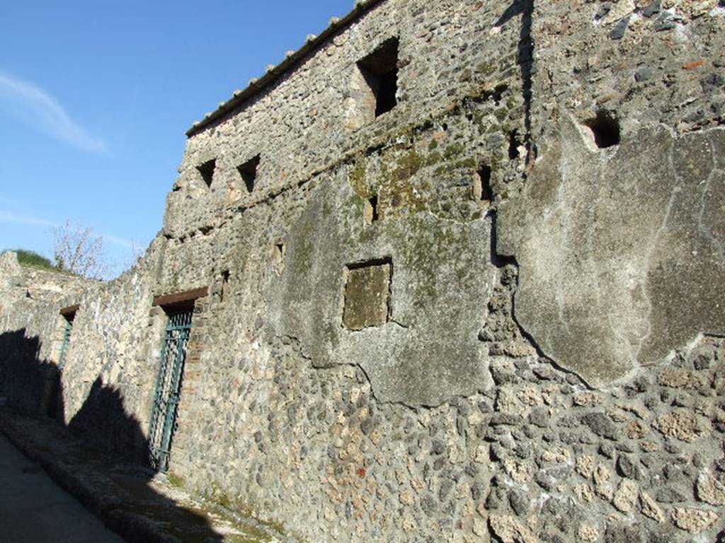 I.11.16 Pompeii. December 2006. Facade. According to Packer, the walls of the facade were built of random rubblework on average between 4.00 and 5.84m in height, but the excavators had extensively restored the upper sections. One quoin faced with opus vittatum was on the south side of the entrance doorway. The facade was stuccoed and some still remains in situ. Two rows of sockets indicated that a sloping projecting roof originally shaded the facade which gained interest from a row of irregularly placed windows.
See Packer, J: Inns at Pompeii: a short survey, in Cronache Pompeiane IV-1978 (p.18-24)