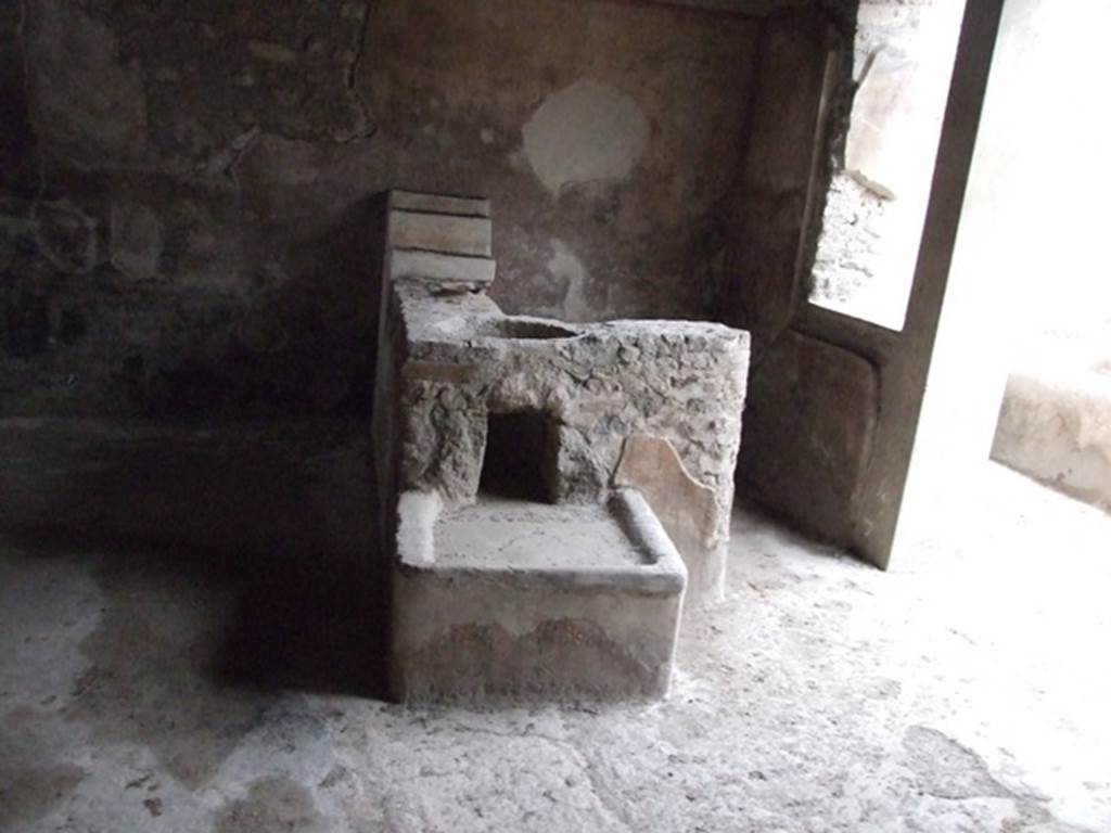 I.11.16 Pompeii. December 2007. Room 1, looking north at bar counter.  According to Packer, against the north wall were three small shelves probably used for the storage of cups, glasses and beakers. Originally there were two containers embedded into the counter, but only the smallest remains in situ. In the larger opening would have been a bronze or lead container, supported  by five brick projections so as to leave space below for coals, an arrangement that was used to heat liquids. The coals were raked underneath the container through a rectangular opening reached from the low hearth attached to the south side of the counter. The counter, shelves and hearth were all stuccoed.