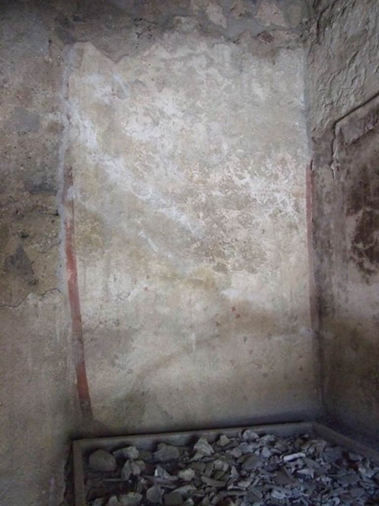 I.12.8 Pompeii. March 2009. Room 10, west wall.  Painted on the upper west wall was a round altar with a genius flanked by two lares with a rhyton and a patera.  On the lower west wall was a garland with painted plants and birds underneath.  See Fröhlich, T., 1991. Lararien und Fassadenbilder in den Vesuvstädten. Mainz: von Zabern. (L26, T:26,1).
According to Giacobello, the legs of the lares used to be visible at the top of the wall, but only their booted legs as their upper parts were destroyed.  See Giacobello, F., 2008. Larari Pompeiani: Iconografia e culto dei Lari in ambito domestico.  Milano: LED Edizioni.  (p.152-3).
According to Curtis, on the west wall was a painting in two parts, both in a bad state of preservation. In the upper part appeared the genius of the family, or owner, sacrificing on an altar which was on his right. Two possible lares were shown, one on the left side of the altar, and the other to the right of the figure near the altar. The lower panel presented a garden scene including three birds, one perched on a branch, one standing on the ground, and one in flight. See Curtis, R.I: The Garum shop at Pompeii, In Cronache Pompeiane, V,1979, (p.20-1)