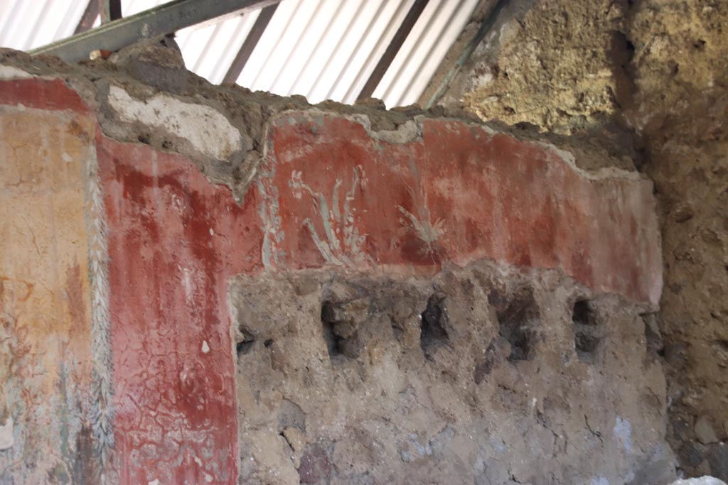 I.12.8 Pompeii. October 2022. 
Peristyle 9, north wall at east end, detail of painted wall above holes for supports of ceiling above latrine 12. Photo courtesy of Klaus Heese.
