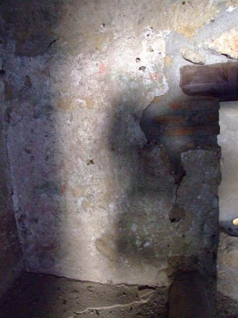 I.12.11 Pompeii. March 2009. Lararium painting on west wall of kitchen, above hearth.  
According to Giacobello, the lararium painting in the south-west corner of the kitchen was on the walls that against which the bench was placed.
It was not very preserved, but showed garlands in red/yellow/green, with underneath them a trace of sky blue.
See Giacobello, F., 2008. Larari Pompeiani: Iconografia e culto dei Lari in ambito domestico.  Milano: LED Edizioni. (p. 154).