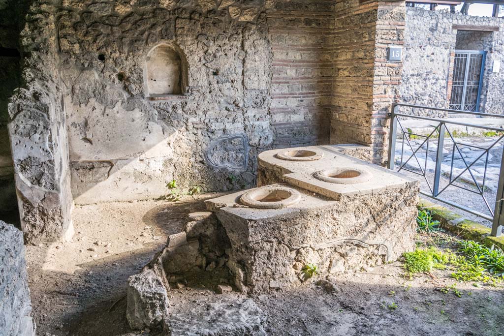 I.14.15 Pompeii. January 2019. Detail of bar/podium with remains of hearth at north end, and east wall with niche. 
Photo courtesy of Johannes Eber.
