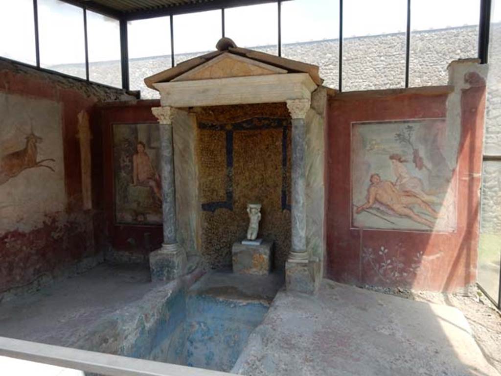 II.2.2 Pompeii. May 2016. Room “k”, summer dining room with biclinium and water feature.
Photo courtesy of Buzz Ferebee.
According to Soprano –
Ubicazione: braccio trasversale dell’euripus. L. summus, m.3.40; l. imus, m.2.78.
Bibliog. Maiuri, Pompei, p.93; idem L’ultima fase edilizia di Pompei (Istituto di Studi Romani, Roma, 1942), p.152 e tav.xlviii;
Maiuri-Pane, Monumenti italiani editi a cura dell’Accad. dei Lincei, serie II, fasc. I, La Casa di Loreio Tiburtino e la Villa di Diomede, p.6 e tav. ii con pianta e sezione;
Della Corte,in “Atti del II Congresso dell’Istituto di Studi Romani”, I, p.19;
I MM Tiburtini di Pompei, in ”Atti e Memorie della Societa Tiburtina di Storia e Arte”, XI-XII, 1931, p.188; Pompei, i Nuovi Scavie l’Anfiteatro, p.66.
Ad est del braccio trasversale dell’euripus che adorna il giardino della casa, s’apre un ninfeo e, dinanzi, il bacino di una vasca rettangolare. 
Ai lati di esso si dispongono i due letti tricliniari in muratura.
Il l. summus era addossato al muro con due lati mentre il l. imus, dista 60 cm. dal muro cui era addossato il ninfeo; le spondae (sponde esterne) di entrambi
i letti sono rialzate. I letti hanno un rivestimento in intonaco rosso, e su quello summus era l’indicazione “Lucius pinxit”, che ci tramanda la firma del pittore dei due dipinti a soggetto mitologico del ninfeo: Narciso al fonte e Piramo e Tisbe.
See Soprano, P. (1950). I triclini all’aperto di Pompei. (In Pompeiana, raccolta di studi per il secondo centenario degli scavi di Pompei. Napoli, Gaetano Macchiaroli, Editore, p.305-6, no.25 (wrongly numbered as I.5.2).