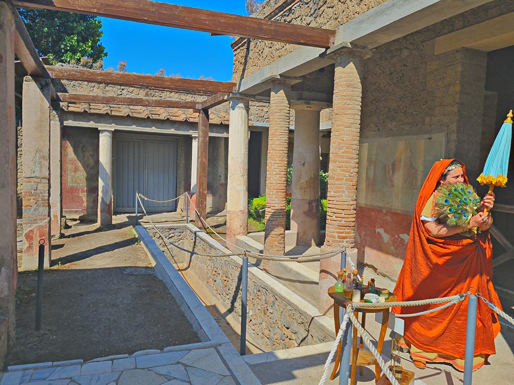 II.2.2 Pompeii. 8th June 2024. 
Room “i”, looking west along upper euripus, with actor playing the part of an ancient pompeian. Photo courtesy of Giuseppe Ciaramella.
Historical reconstruction entitled L’altra Pompei prende vita (The other Pompeii comes to life).