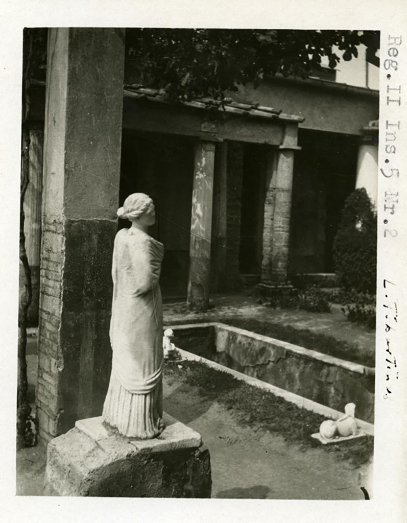 II.2.2 Pompeii, but shown as II.5.2 on photo. Pre-1937-39. 
Room “i”, looking north-west towards west end of upper euripus with statue of Muse Erato or Mnemosyne. 
The statue of the muse Erato or Mnemosyne and a sphinx (SAP inventory number 2930) are shown.
Photo courtesy of American Academy in Rome, Photographic Archive. Warsher collection no. 1903.
The statue originally stood on one of the six bases along the southern side of the canal, which probably held statues of muses, of which only this and one other have been found. Jashemski describes the two surviving statues as, one of Polyhymnia (SAP 2917) and the second of Mnemosyne (SAP 2909).
The names on her photographs however are reversed. 
See Jashemski, W. F., 1993. The Gardens of Pompeii, Volume II: Appendices. New York: Caratzas. (p. 80-1, Figs 84-85).