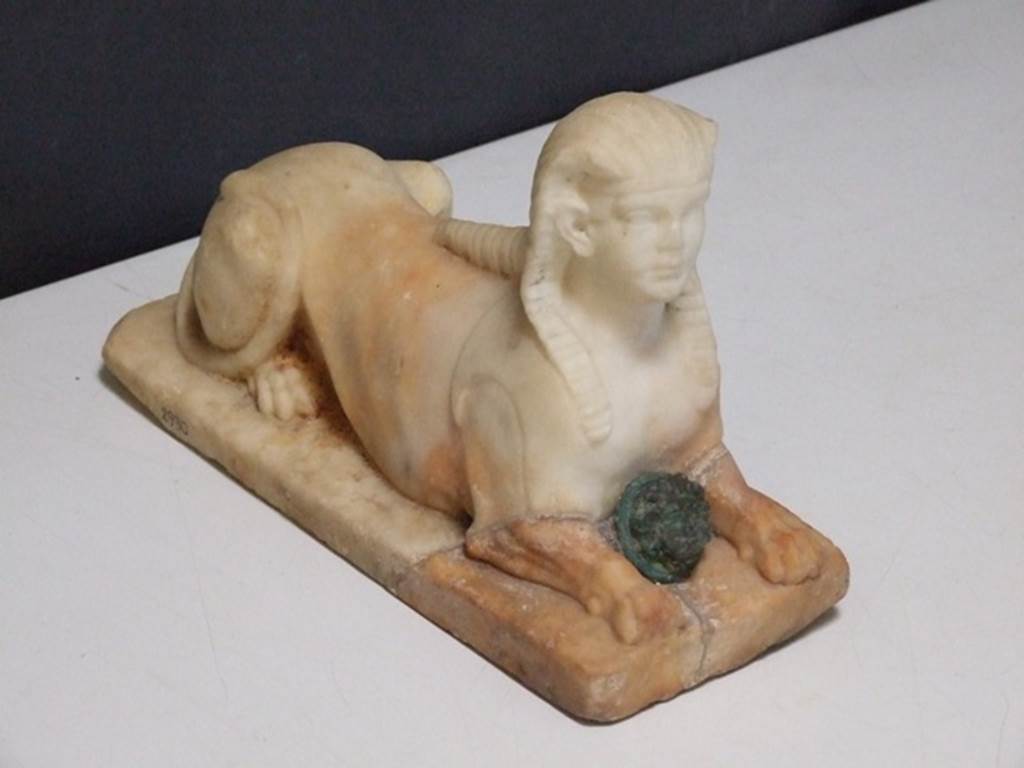 II.2.2 Pompeii.  March 2009. Room “i”. White marble statuette of Sphinx, with a face of a bronze gorgon between the front legs.   Found on the north side of the upper euripus in the garden in 1920.  SAP inventory number 2930.