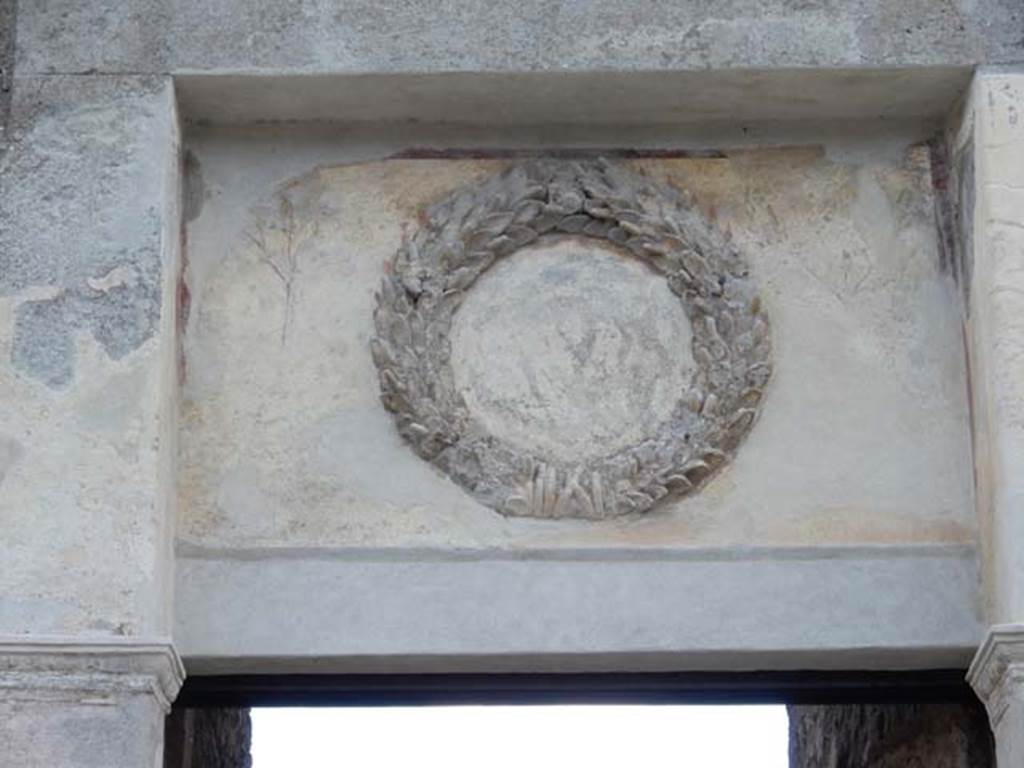 II.2.4 Pompeii. May 2016. Detail of emblem decoration above entrance doorway.
Photo courtesy of Buzz Ferebee.
