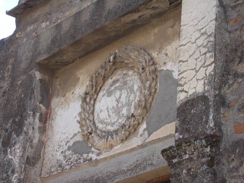 II.2.4 Pompeii. September 2005. Above the entrance doorway, one can still see the Augustan emblem. This is a crown of oak between two laurel branches.