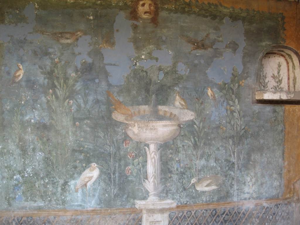 II.3.3 Pompeii. July 2007. Room 11, detail from west panel of south wall of peristyle. 
Wall painting of fountain with garden, mask and birds. Photograph courtesy of Kathryn Breen.