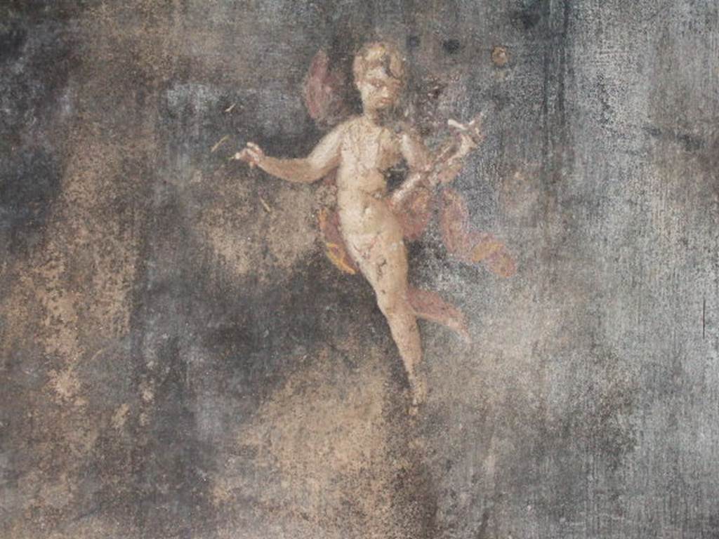 II.3.3 Pompeii. December 2005. Room 6, south wall of triclinium. 
Wall painting of Amorino or flying cupid holding a baetylus (or alabaster vase) in his left hand.