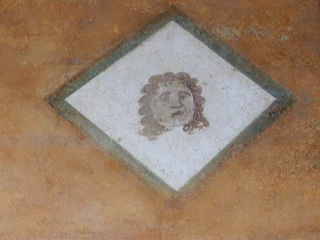II.3.3 Pompeii. May 2016.  Room 11, painted face from south end of upper west wall of west portico, above doorway to room 12. Photo courtesy of Buzz Ferebee.