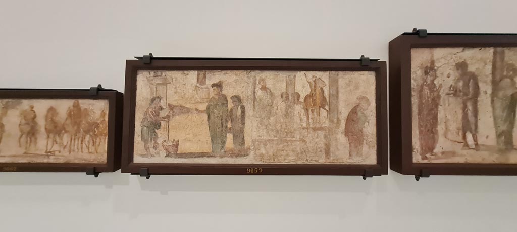 II.4.3 Pompeii. April 2023. Paintings of the Forum frieze, on display in “Campania Romana” gallery in Naples Archaeological Museum.
In centre (inv. 9059) – Mendicante e donne; tre uomini presso statua equestre e donna. 
(Beggar and women; three men by an equestrian statue and woman).  Photo courtesy of Giuseppe Ciaramella.
