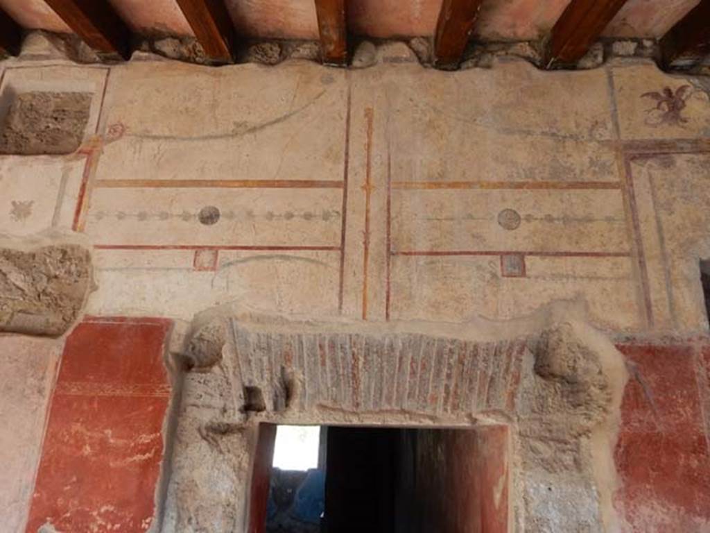 II.4.6 Pompeii. May 2017.  Detail of south wall decoration above doorway to apodyterium. 
Photo courtesy of Buzz Ferebee.
According to PPM, on top of the aedicula is a mermaid with fish in her hands.
See Carratelli, G. P., 1990-2003. Pompei: Pitture e Mosaici: Vol. III.  Roma: Istituto della enciclopedia italiana, p. 211.