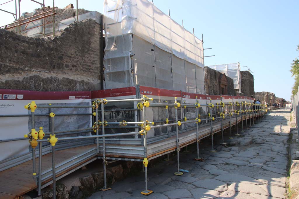 II.4.7 Pompeii. September 2017. Looking west along Via dell’Abbondanza during restoration/conservation work.
II.4.7 is the entrance behind the scaffolding with plastic sheeting, II.4.6 can be seen towards the right.
Photo courtesy of Klaus Heese.