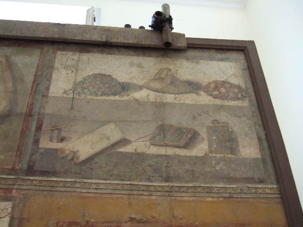 II.4.10 Pompeii. Detail of upper wall from tablinum of Praedia di Giulia Felice (Julia Felix).  
Painting showing two piles of coins, a bag of money, pen and ink, a scroll, double and single wax tablets and writing instruments. 
Now in Naples Archaeological Museum. Part of inventory number 8598. 
According to Andersson, although heaps of money are depicted above wax tablets on the legendary wall painting from the property of Julia Felix (II 4.1 – 12), archeologically speaking, money has never been found near wax tablets.
See Andersson E. B., 2018. The Economic Centre of Pompeii Revealed by Roman Cash Keeping, in Archaeology and Economy in the Ancient World, p. 160 and fig. 4.