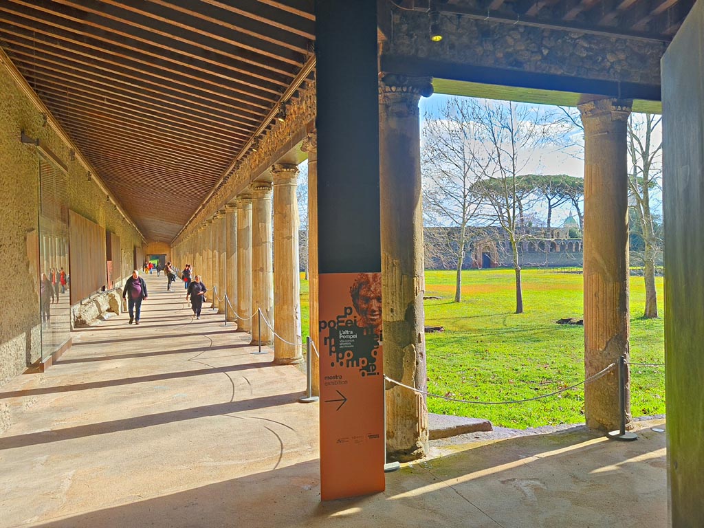 II.7.8 Pompeii. March 2024. 
Looking east along north portico, with advertisement for exhibition, signed to the right. Photo courtesy of Giuseppe Ciaramella.