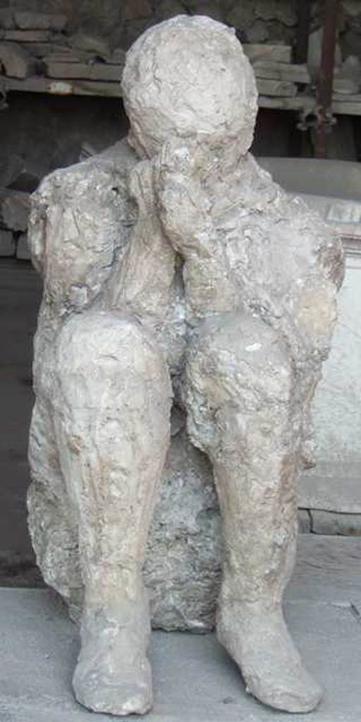 II.7.11 Pompeii. Palaestra. Plaster cast of victim found near the latrine, perhaps found crouching on the ground with his back against the wall of the east portico. Now in VII.7.29 Forum granary market.