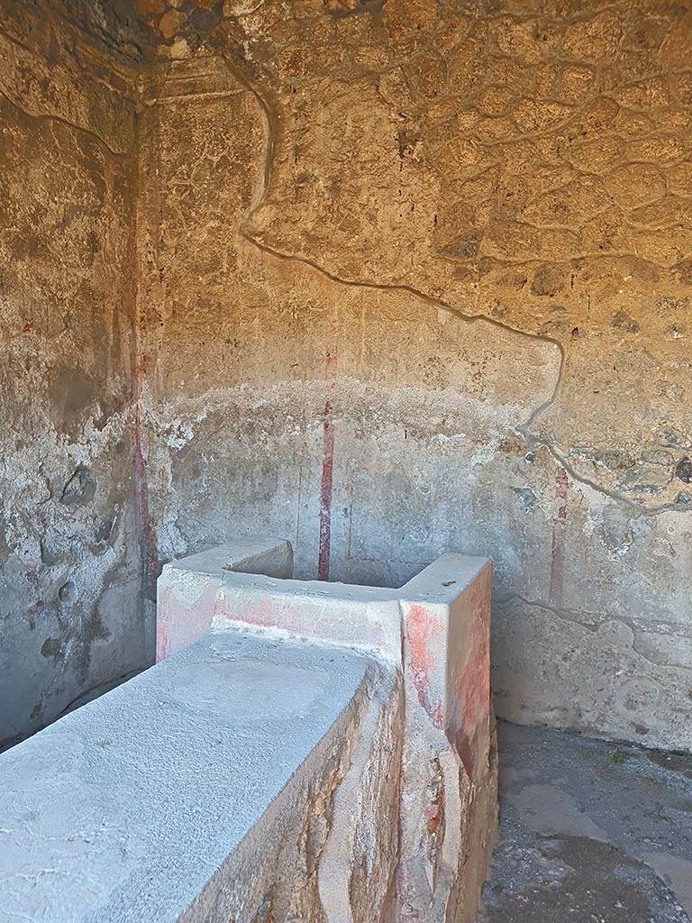 II.8.3 Pompeii. October 2024. 
Looking east from entrance doorway towards hearth at end of bar-counter, and decorated east wall. 
Photo courtesy of Giuseppe Ciaramella.