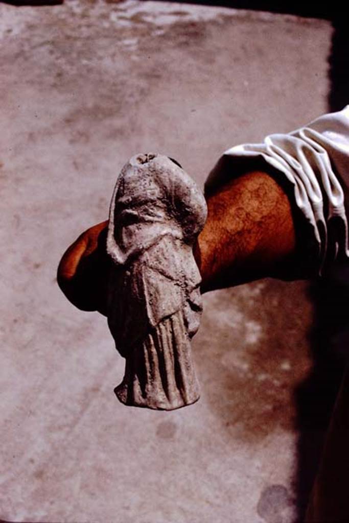 II.8.6 Pompeii. 1972. Terracotta votive offering of a small draped figure with traces of red on the drapery, (0.155m high), found near the lararium by the original1953-54 excavators. (Pompeii inv. no: 10150). Photo by Stanley A. Jashemski. 
Source: The Wilhelmina and Stanley A. Jashemski archive in the University of Maryland Library, Special Collections (See collection page) and made available under the Creative Commons Attribution-Non Commercial License v.4. See Licence and use details. J72f0317