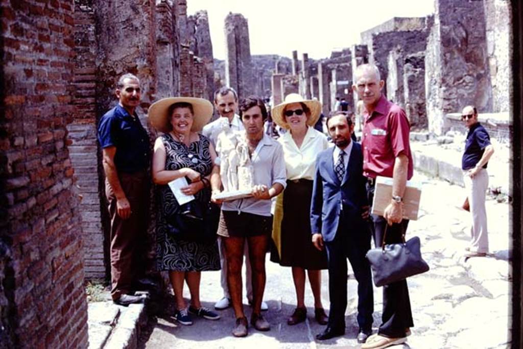 II.8.6 Pompeii, 1973. The statue of Hercules which was found in the lararium in his garden, being carried along the Via dell’Abbondanza.
Photo by Stanley A. Jashemski. 
Source: The Wilhelmina and Stanley A. Jashemski archive in the University of Maryland Library, Special Collections (See collection page) and made available under the Creative Commons Attribution-Non Commercial License v.4. See Licence and use details.
J73f0610
According to Wilhelmina, 
“Guiseppina Cerulli had agreed that Hercules could be returned to his garden for the final photos. He was triumphantly carried along the Via dell’Abbondanza accompanied by admirers and placed again in his shrine. All of her workers wanted their pictures taken with him”.
See Jashemski, W.F., 2014. Discovering the Gardens of Pompeii: Memoirs of a Garden Archaeologist, (p.207).