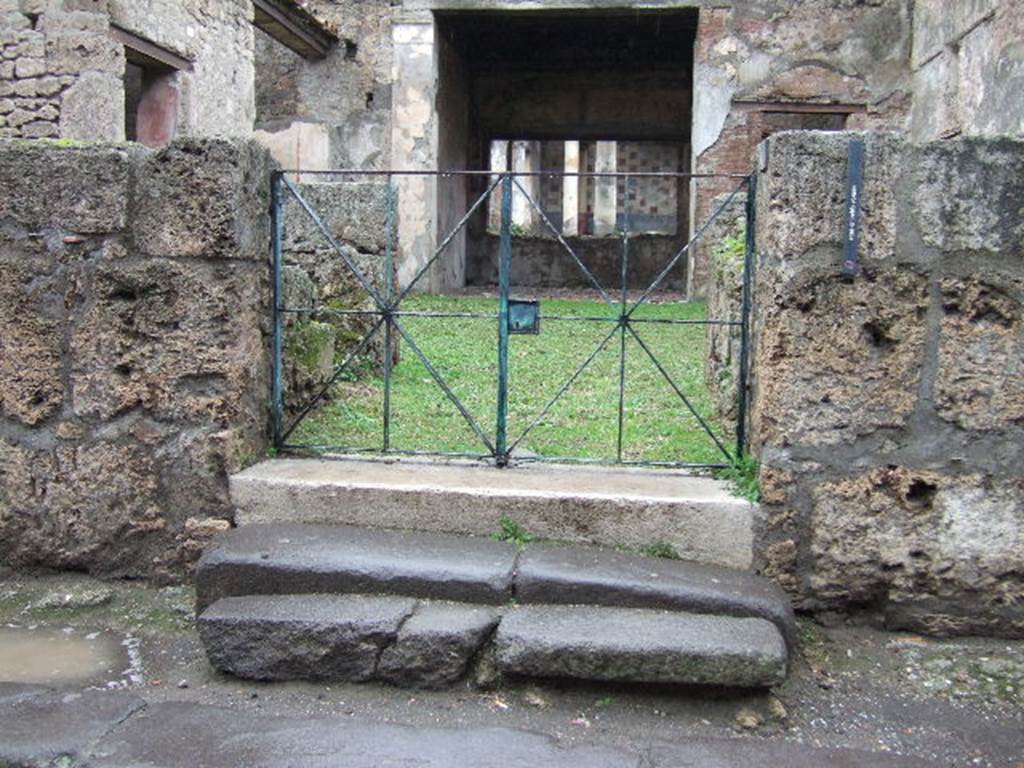 III.2.1 Pompeii. December 2005. Entrance doorway. Upon excavation, and 2.60m height above the pavement level, a bronze cylindrical door-bell with iron bell-clapper (height 0.13m) was found on 3rd January 1914. According to Della Corte, the threshold of the door to this house was reached by climbing two steps of travertine.At the moment of the catastrophe in 79AD the door was closed.This was proved by the finding of the door locking apparatus (door-lock, key, door-handle and bolt) collected in the up-right of the nearby door-shutter. See Della Corte, M, in Notizie di Scavi, 1914, (p. 75 and p.104)