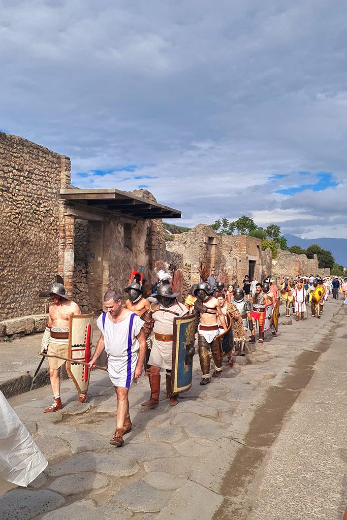 III.5.2 Pompeii, on left. 28th September 2024. 
Gladiators on their way to the Forum from the Amphitheatre, during “Ludi Pompeiani” event.
Looking east along north side of Via dell’Abbondanza. Photo courtesy of Giuseppe Ciaramella.