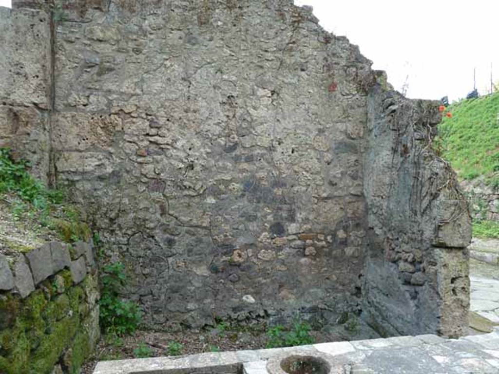 III.8.8 Pompeii. May 2010. West wall of bar-room. According to the Giorn. dei soprastanti, near the right entrance pillar of the bar-room at the height of about a metre from the ground, a human skeleton was found in the lapilli. Found leaning against him was a large broken amphora in many pieces. Found between the podium and the amphora was a large grey slab of marble. See Notizie degli Scavi di Antichità, 1905, (p.275)