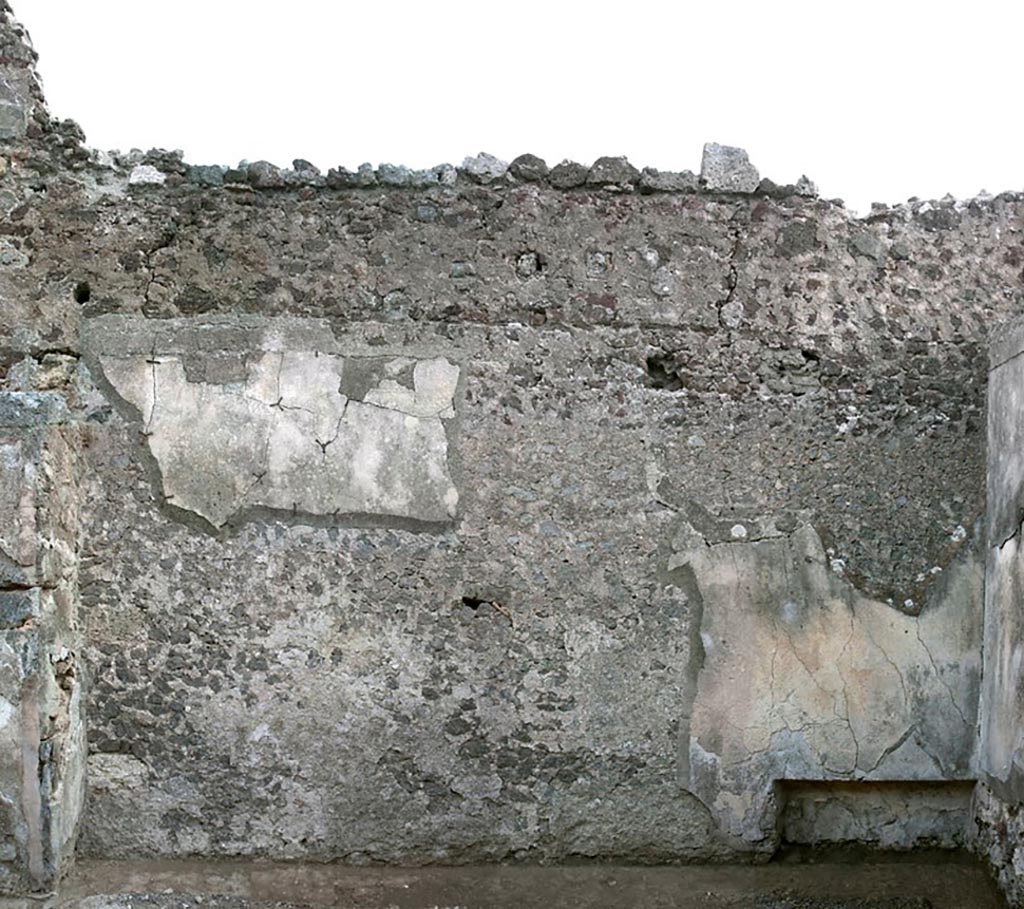 V.1.3 Pompeii. c.2008-10.  
Room 4, triclinium, east wall, with niche/recess at south end. Photo by Hans Thorwid.
“Almost the entire niche is covered by plaster. 
In the S corner and along the floor there are remains of black bands. Also the upper part has minor traces of black. 
There is modern plaster in a small area in the middle of the niche, and to some extent also on the S side. 
The N side is covered with modern mortar.”
Photo and words courtesy of the Swedish Pompeii Project.