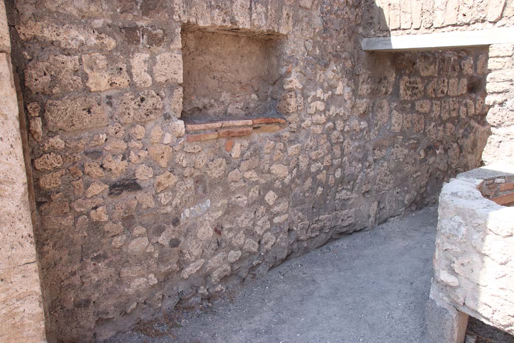 V.1.5 Pompeii. September 2021. 
Looking towards west wall with square niche/recess and doorway into rear room. Photo courtesy of Klaus Heese.