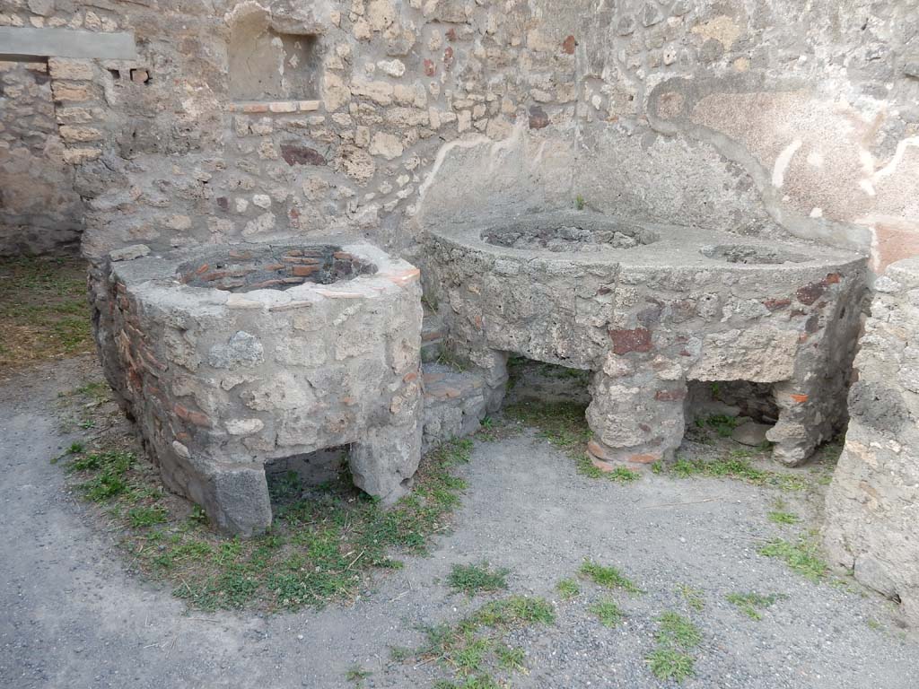 V.1.5 Pompeii. June 2019. 
North wall with doorway to rear room, and niche set into wall, with boilers against the north wall and north-east corner. 
Photo courtesy of Buzz Ferebee.