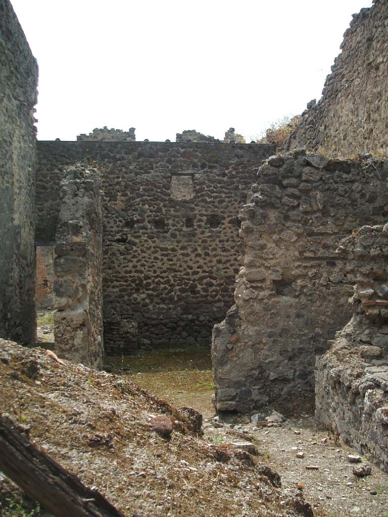 V.1.10 Pompeii. May 2005. Looking west from doorway into kitchen and workshop/stable area. 
According to Boyce, in the kitchen on the wall beside the hearth was a lararium painting (on the right of this photo). 
No longer visible.
See Boyce G. K., 1937. Corpus of the Lararia of Pompeii. Rome: MAAR 14. (p.32)