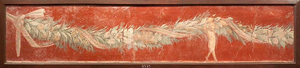 V.1.18 Pompeii. Tablinum “g”, south wall. Fresco with ribbon wound in a garland of flowers, grapes, fruit and corn, and held up by a cupid.
Now in Naples Archaeological Museum. Inventory number 8525.
According to Sogliano – this was from the tablinum, on a yellow background – 
A heavy garland of flowers wrapped in a ribbon was supported by a naked Cupid, of which only one was preserved.
(Bull. Inst. 1877, p.23)
See Sogliano, A., 1879. Le pitture murali campane scoverte negli anni 1867-79. Napoli: Giannini. (p.63, no.365).