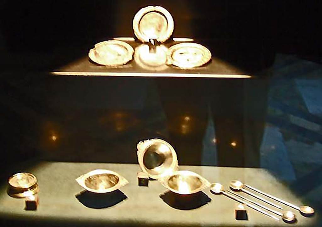 V.1.18 Pompeii. Silver found in the ala “e”. 
Now in Naples Archaeological Museum.
Top left to bottom right:-
Three small saucers with traces of gilding. Inventory numbers 110850, 110851, 110852.
Round gilded base. Inventory number 110865.
Three round conical bodied cups. Inventory numbers 110853, 110854, 110855.
Four spoons (cochlearia). Inventory numbers 110857, 110858, 110859, 110860.
