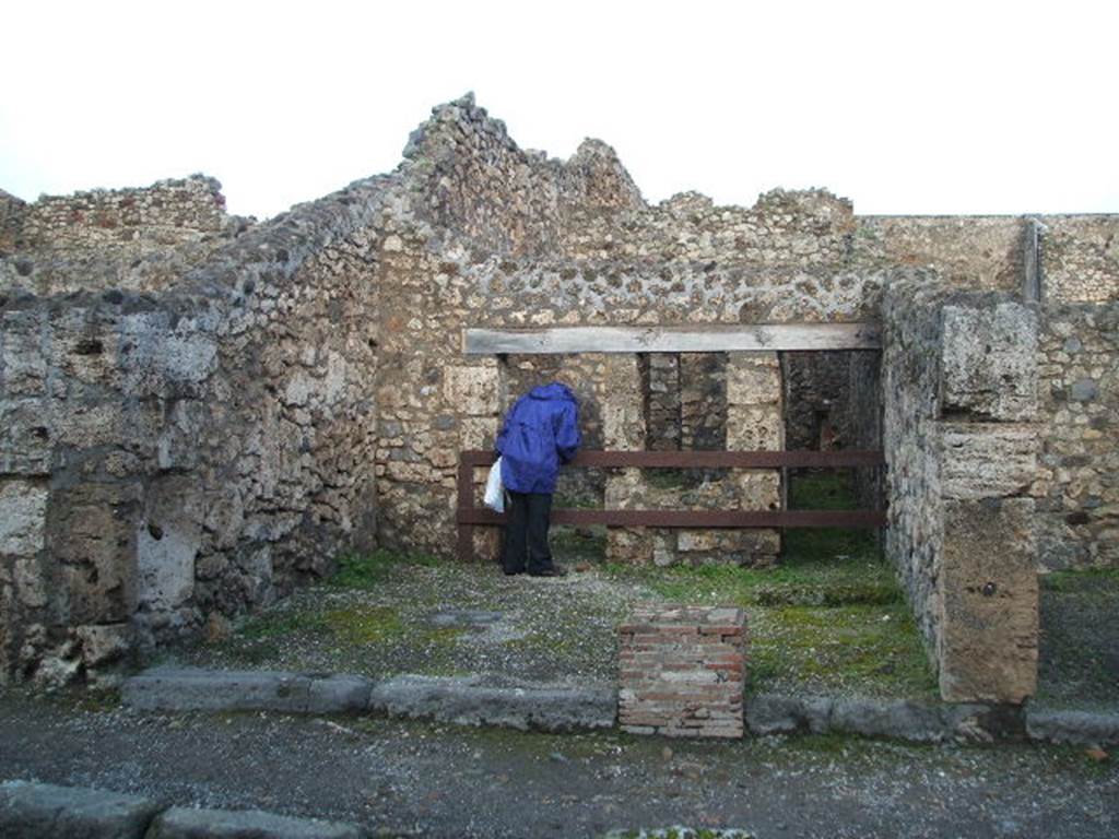 V.1.20 Pompeii. Entrance. December 2004. V.1.20 on left and V.1.21 on right.
According to Mau, V.1.20-21 was a shop or rather workshop, next to the entrance to the steps (21) to the upper rooms, and areas at rear. The steps were not immediately by the door threshold, but were a little way back, so that the steps were also accessible from the workshop. The decorative painting of the workshop, was executed in the last style of Pompeii, and without interest. On the middle compartment of the left wall, we see represented a standing Bacchus crowned with vine, naked except for a blue garment on his left shoulder and right arm, and, as it seems, boots. The right arm raised with thyrsus, while the left hand poured the wine into the mouth of the lying down panther from a jug. The figure was 0.55 high.  Hardly recognisable were the paintings from the side panels of the same wall: to the right there were some beasts, perhaps goats. At the rear on the left, was a room used probably by the customers of the workshop; it received light from the workshop itself by means of a window to the right of the entrance doorway. Another door at the rear of the room, whose walls were covered with red coloured plaster, and a corridor that bordered it on the right, both lead to the kitchen. The kitchen had the lararium painting on the left wall, above both the hearth and the well that was to the right, of which not much remained other than a part of the serpent that was shown going towards the doorway of the small room mentioned, away from the hearth. To the right of the entrance to the kitchen there was a low raised quadrangle of material, of uncertain use.  At the rear of the kitchen on the left, near to the well and the hearth, a rather high doorway gave access to a small room, 1.13 wide, 1.86 deep of the usual form, but of which I couldn't guess the use. The floor was of opus Signinum; all around ran a gutter, separated from the space it was surrounded by a small wall 0.24 high, also covered by opus Signinum, the gutter at the front corner to the right, crossing the wall, led to the middle part of the room, which towards this point was lower and here had a drain into the well. A vaulted window, in the right wall, gave into a rough room of equal depth, accessible from the kitchen by a low door; the window was made in a manner that its floor lowered towards this last room.  See Mau, Bdl (1877), p.17-18
