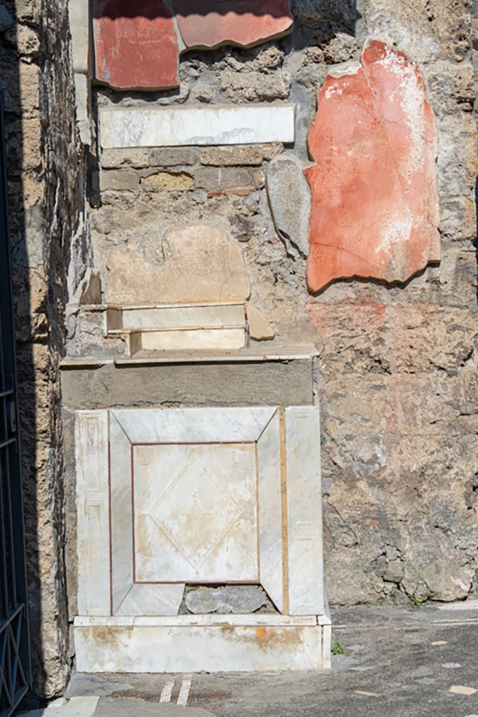 V.1.26 Pompeii. October 2023. 
Room “b”, north-west corner of atrium with marble lararium. Photo courtesy of Johannes Eber.