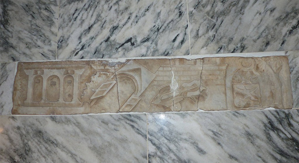 V.1.26 Pompeii. Lararium in north-west corner of atrium “b”. The upper marble relief which was stolen in 1975.
It was discovered in 2023 in a residential house in Belgium. It had been sold to a Belgian family as a souvenir whilst they were on holiday in 1975. 
It was displayed set in the wall above the stairs to the basement of their house for over 50 years.
Following an investigation by Belgian Judicial police, and a visit by a delegation from Pompeii to confirm it is the original marble relief, it is hoped it will return to Pompeii.
See https://www.thehistoryblog.com/archives/69083