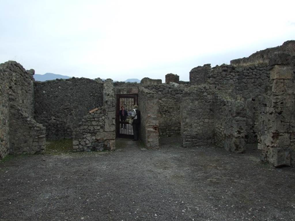 V.2.1 Pompeii. December 2007. Room 1, looking south across the atrium to the entrance.
On the south side of the atrium are the doorways to our rooms 2, on the left, and room 4, on right of entrance corridor.
The doorway to room 5 can be seen on the right.
(BdI, room letters on plan) - Doorway to room “u”, on left of entrance corridor, room “k” on right of entrance corridor, room “l” on right-hand side.
According to Mau, in the distribution of the rooms, this house did not follow the regular scheme but had obeyed the needs of the confined space.  
Around the atrium were three cubicula, (k, l and u), a storeroom or cella penaria (s), and the stairs to the upper floor (n); next to the tablinum and accessible from it were two spacious tricliniums (“p and r”), of which (“r”), which had a wide window in its north wall onto the garden could have been called the summer triclinium, and the smaller room with wide entrance (“o”) could have been used for family dinners.
See Mau, Bullettino dell’Instituto di Corrispondenza Archeologica (DAIR), 1885, p.158.
According to PPM,  
The atrium with a similar red zoccolo, divided into compartments, had the middle zone of the walls with raw (rough) plaster.  
The three cubicula (“k”, “l” and “u”) had tripartite walls in panels with vignettes (birds, deer, griffins, only in “l” a medallion with painted masks was preserved) in “k”, these were executed more crudely; in “u”, on the south wall in the lunette was preserved a painted basket from which figs had fallen. 
See Carratelli, G. P., 1990-2003. Pompei: Pitture e Mosaici: Vol. III. Roma: Istituto della enciclopedia italiana, (p.774).