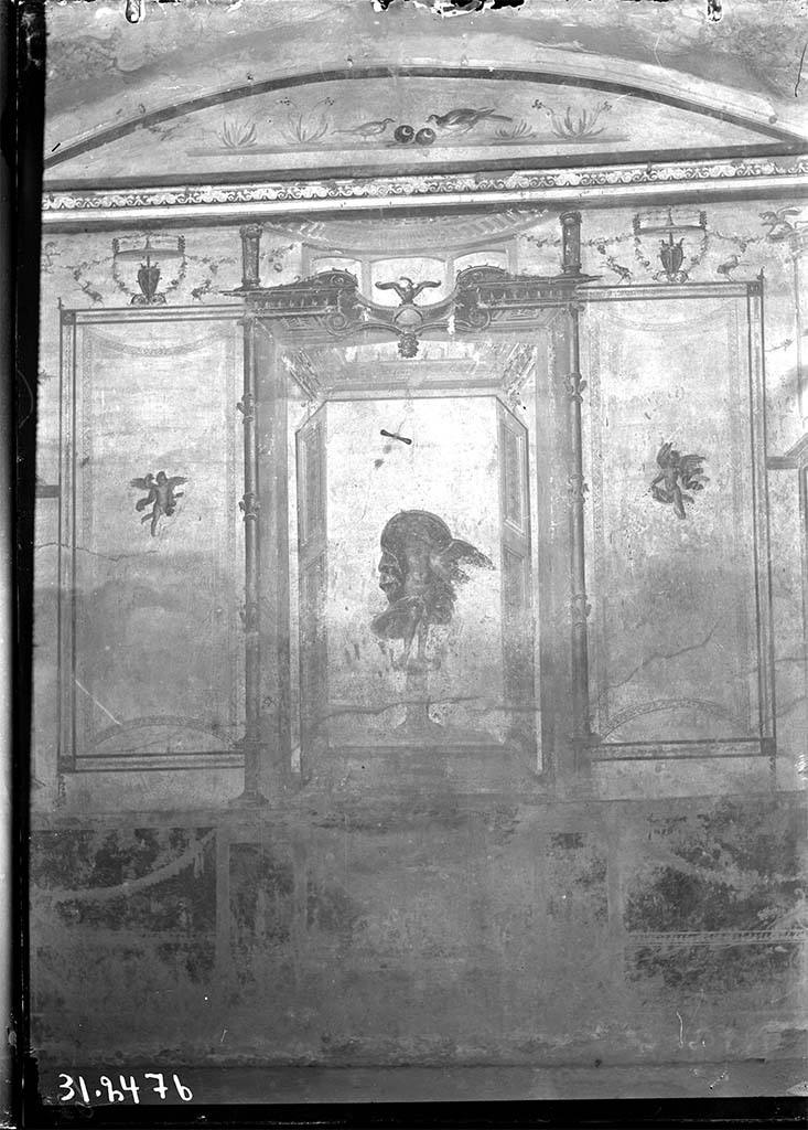 V.2.1 Pompeii. 1931? Room 8, looking towards west wall.
DAIR 31.2476 Photo © Deutsches Archäologisches Institut, Abteilung Rom, Arkiv. 
The zoccolo was red subdivided with panels with carpet borders and garlands.
In the centre was Leda and the Swan in an aedicula with doors at each side and with an eagle on a globe above.
In the side panels were carpet borders, curved on the short sides and with cupids in the centre of each panel and above were goats and garlands.
In the lunette above were birds with fruit and with flowers at the sides.
See Carratelli, G. P., 1990-2003. Pompei: Pitture e Mosaici: Vol. III. Roma: Istituto della enciclopedia italiana, p. 776-7.