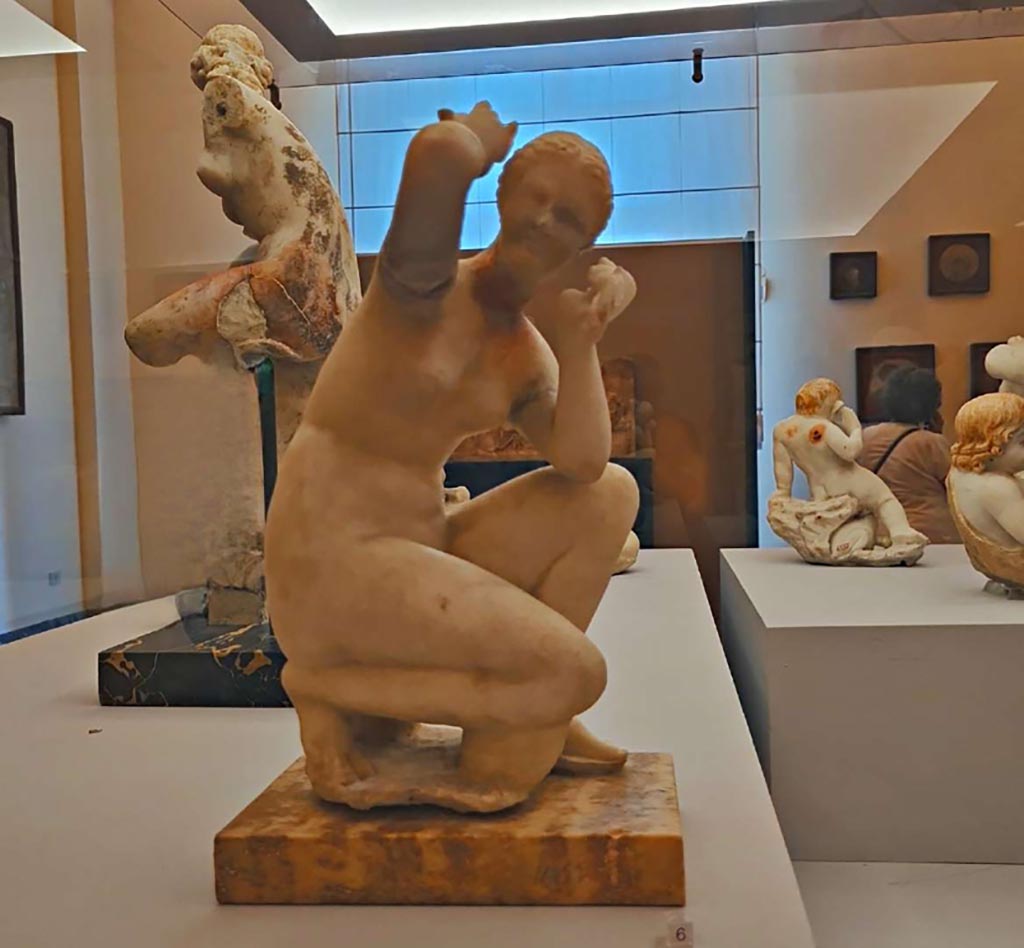 V.2.4 Pompeii. October 2023. Marble statuette of a crouching Venus. Photo courtesy of Giuseppe Ciaramella. 
On display in “L’altra MANN” exhibition, October 2023, at Naples Archaeological Museum, inv. 114536.
According to Carrella -
The statue of the crouching Venus was found in fragments in the impluvium of the atrium, on 6th February 1884.
See Marmora Pompeiana nel Museo Archeologico Nazionale di Napoli: Studi della SAP 26, (p.75, B11).