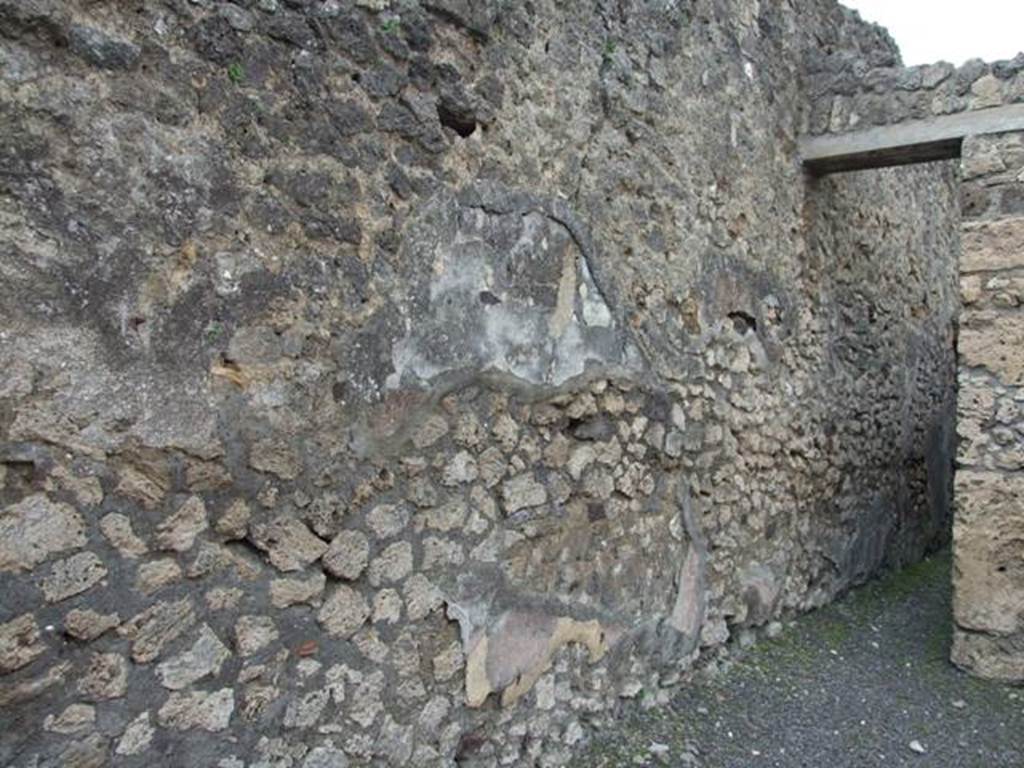 V.2.13 Pompeii. March 2009. Looking north along west wall of thermopolium.
According to NdS, this thermopolium had a sales counter and a small hearth.
On the west wall Sogliano could see the remains of a painted lararium, with a serpent sliding towards an altar on the left.
At the rear was located the room for the customers, which was bordered by a corridor to the latrine.
See Notizie degli Scavi di Antichità, 1896, (p.438)
According to Mau in BdI, the steep stairs to the upper rooms also leaned against this wall, and at a height of 3.25 the holes for the beam supports for the upper floor could be seen.